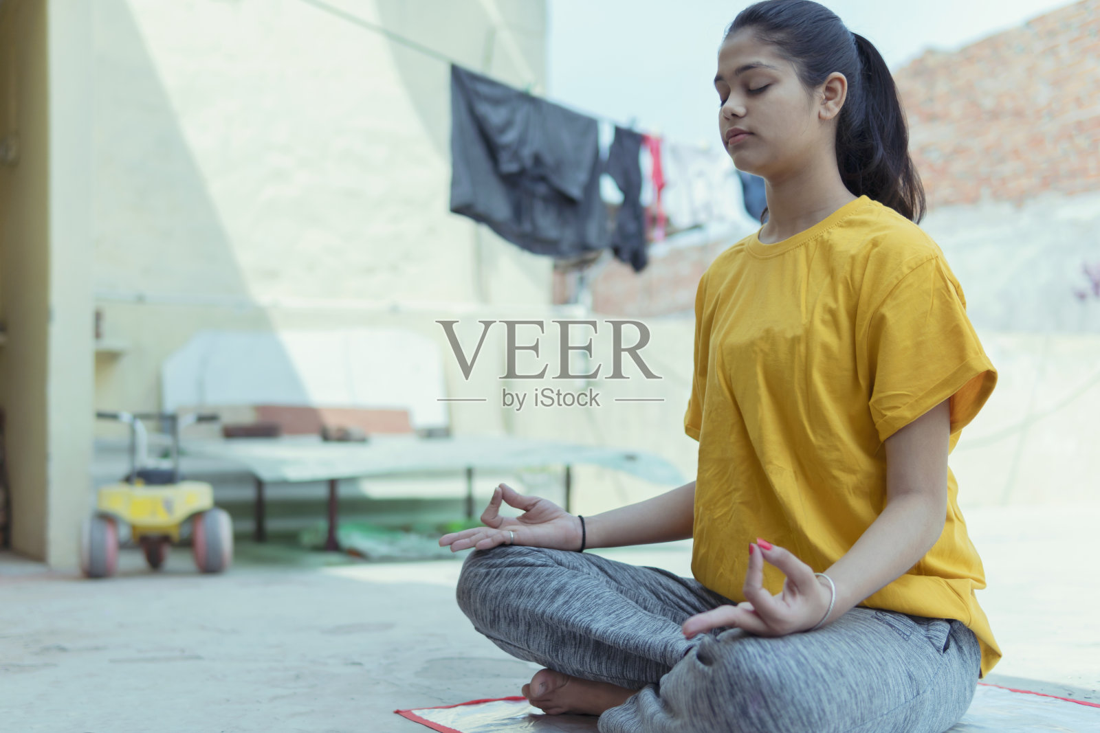 女孩在屋顶上莲花姿势沉思。照片摄影图片