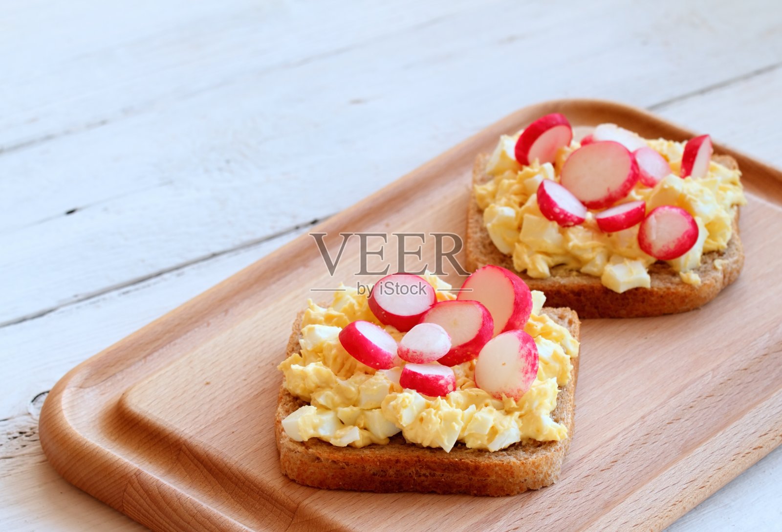 鸡蛋沙拉涂在全麦吐司上，配上萝卜和韭菜。照片摄影图片