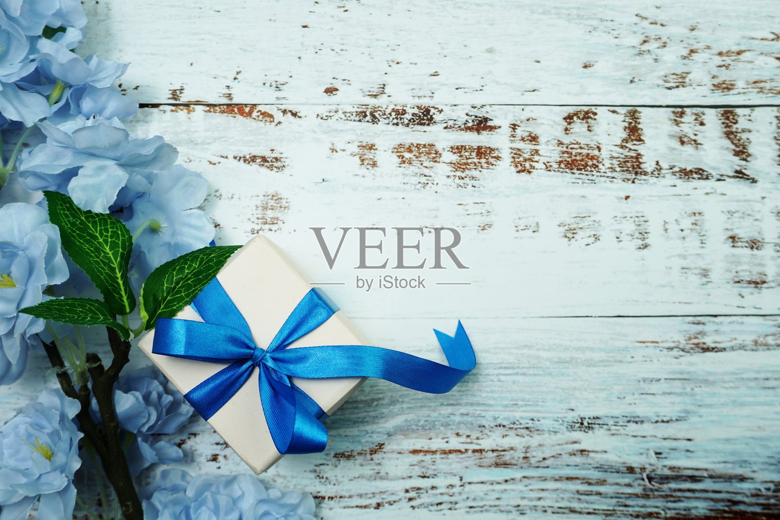 蓝色礼品盒和木制背景上的花朵装饰照片摄影图片