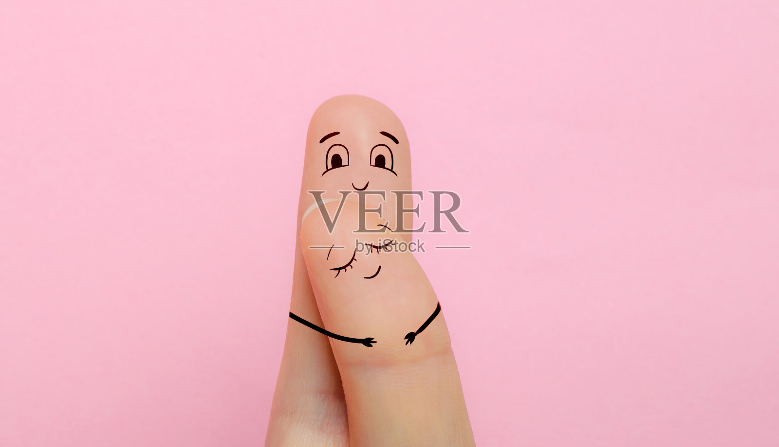 两根手指画着一对异性恋夫妇的脸，一男一女在粉红色的背景中微笑和高兴。没有人的爱和关系的概念照片摄影图片