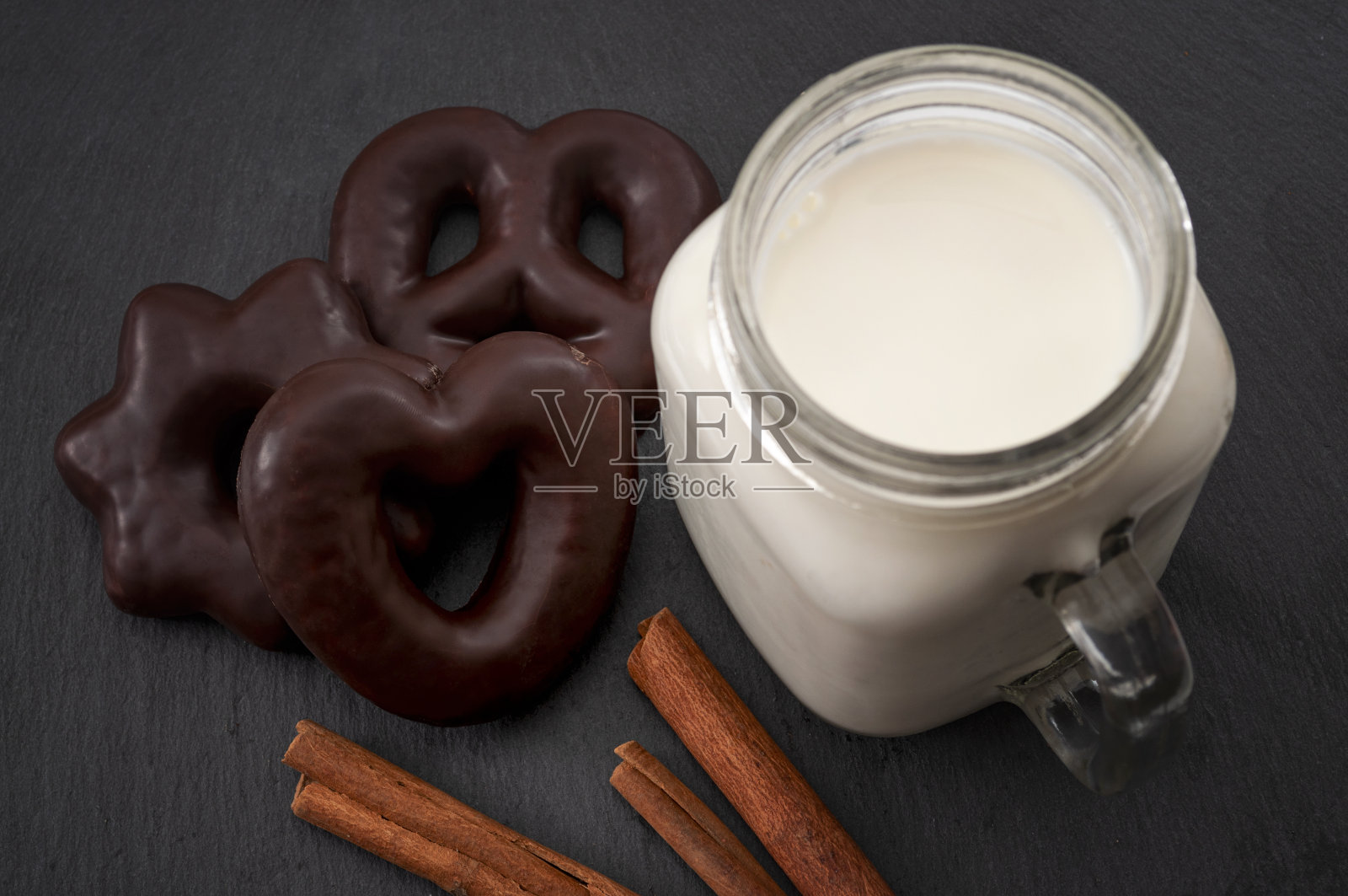 圣诞快乐和传统节日饼干概念巧克力姜饼心，星星和椒盐卷饼形状，肉桂棒和一杯牛奶为圣诞老人照片摄影图片