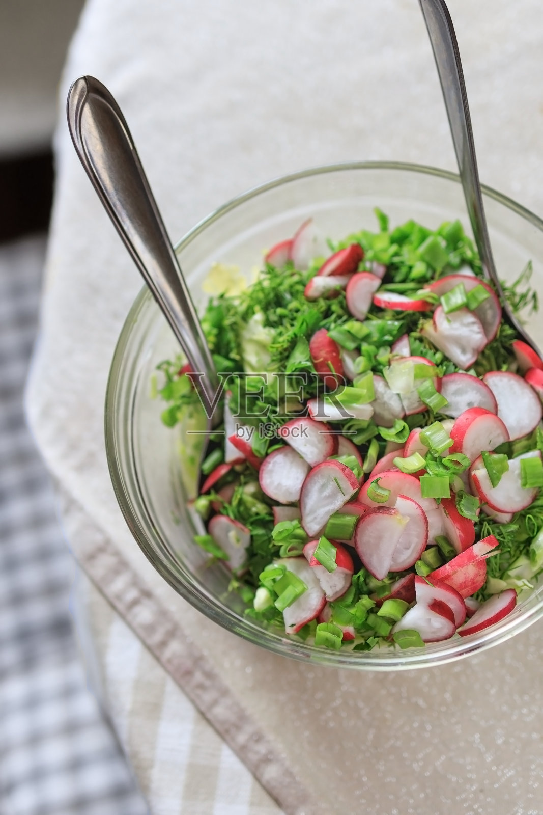 新鲜的春季健康天然沙拉萝卜蔬菜，调味青葱，卷心莴苣，卷心菜在透明的盘子上的桌子。从上面的观点照片摄影图片