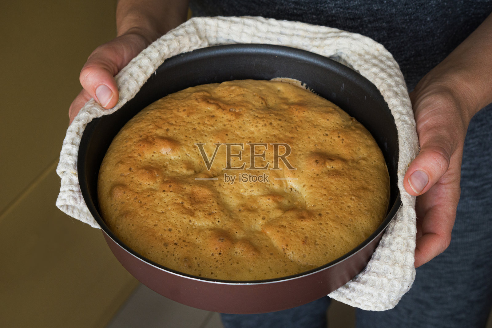 一个拿着刚烤好的派的女人。女人把美味的馅饼放在桌子上。家庭主妇把苹果派送到餐桌上。照片摄影图片