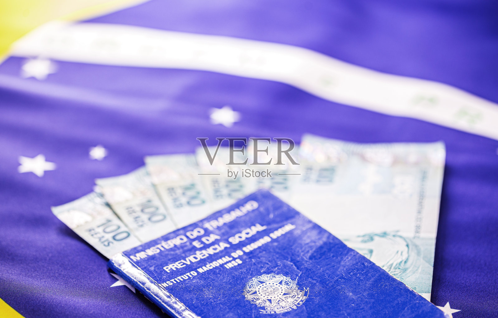 600雷亚尔和100雷亚尔纸币一起印在旧工作卡上，背景是巴西国旗。巴西金融危机的概念形象。照片摄影图片