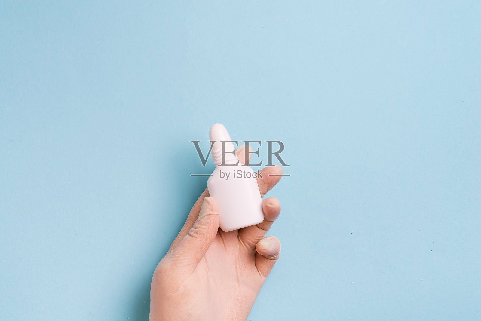 妇女的手在医疗手套持有安瓿在浅蓝色的背景。照片摄影图片