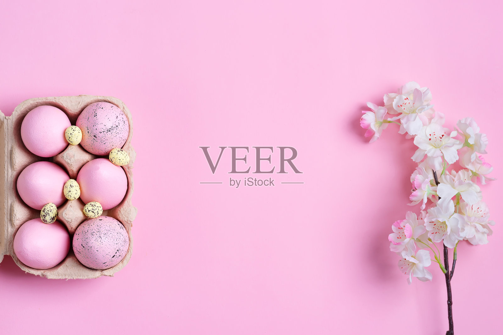 复活节的节日框架，从纸盒手工粉色彩蛋和盛开的樱桃枝在同一颜色的背景。照片摄影图片