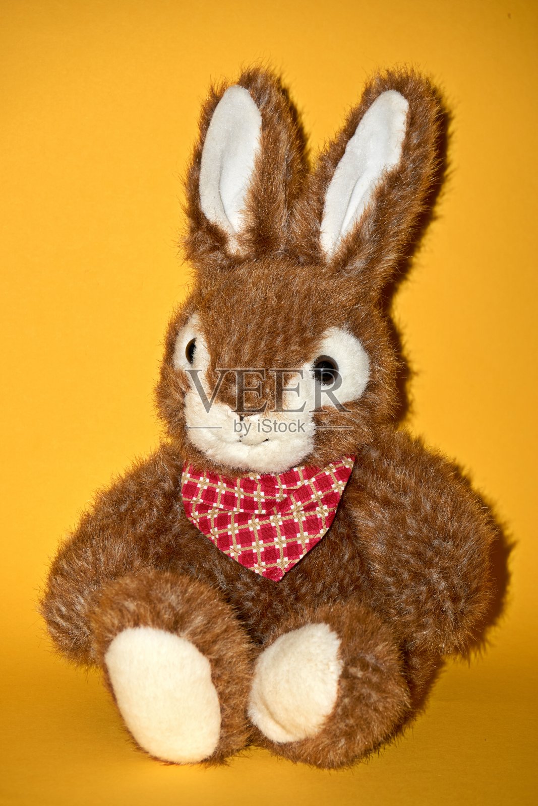 毛绒复活节兔子坐在黄色的背景。照片摄影图片