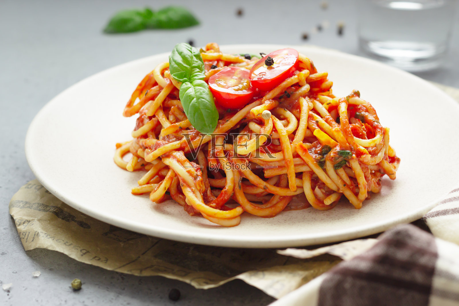 美味的素食意大利面，配上番茄酱、罗勒叶和新鲜的圣女果。浅灰色混凝土背景。关闭了。照片摄影图片