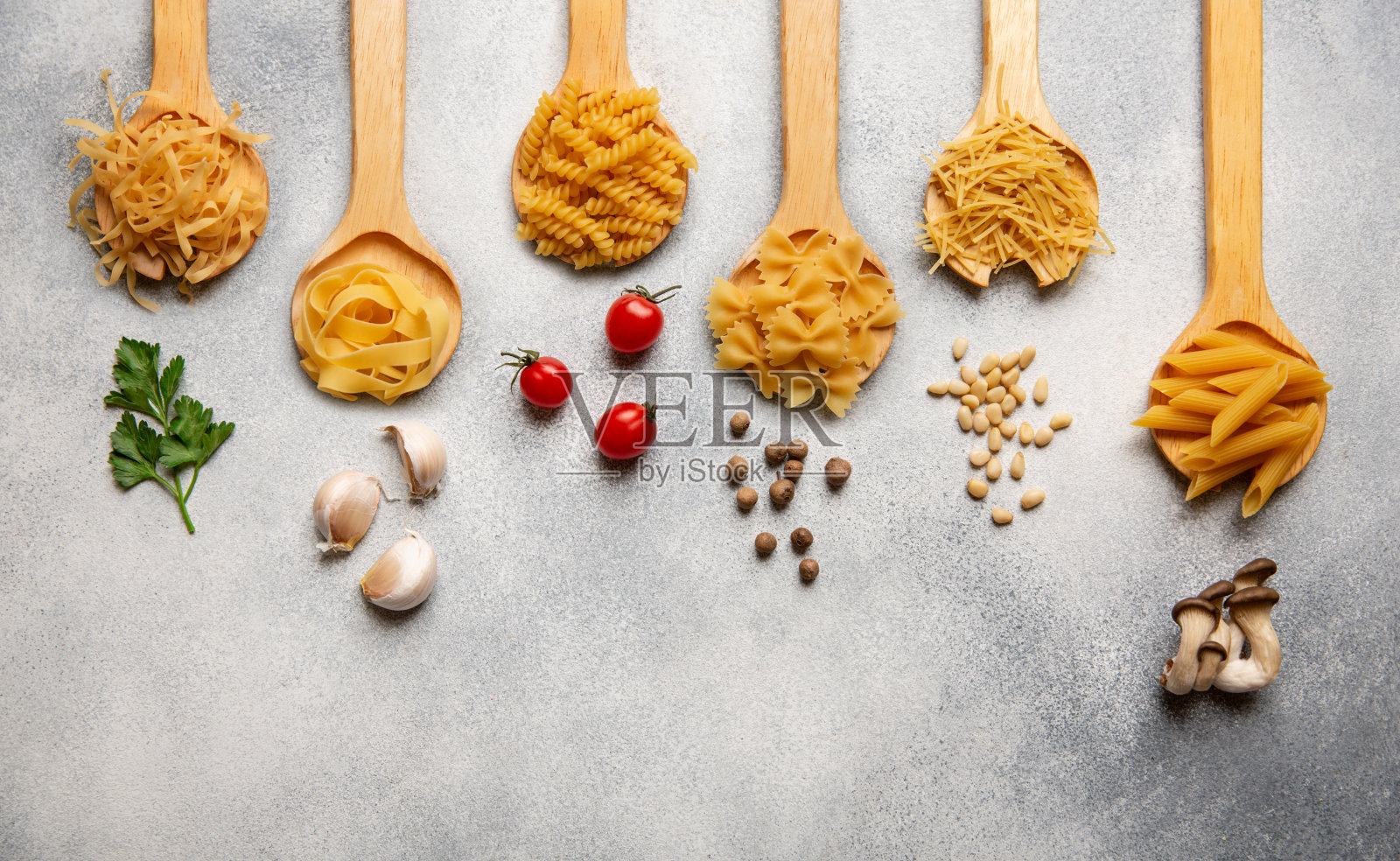 各种各样的意面放在木勺上，配上配料。前视图。照片摄影图片