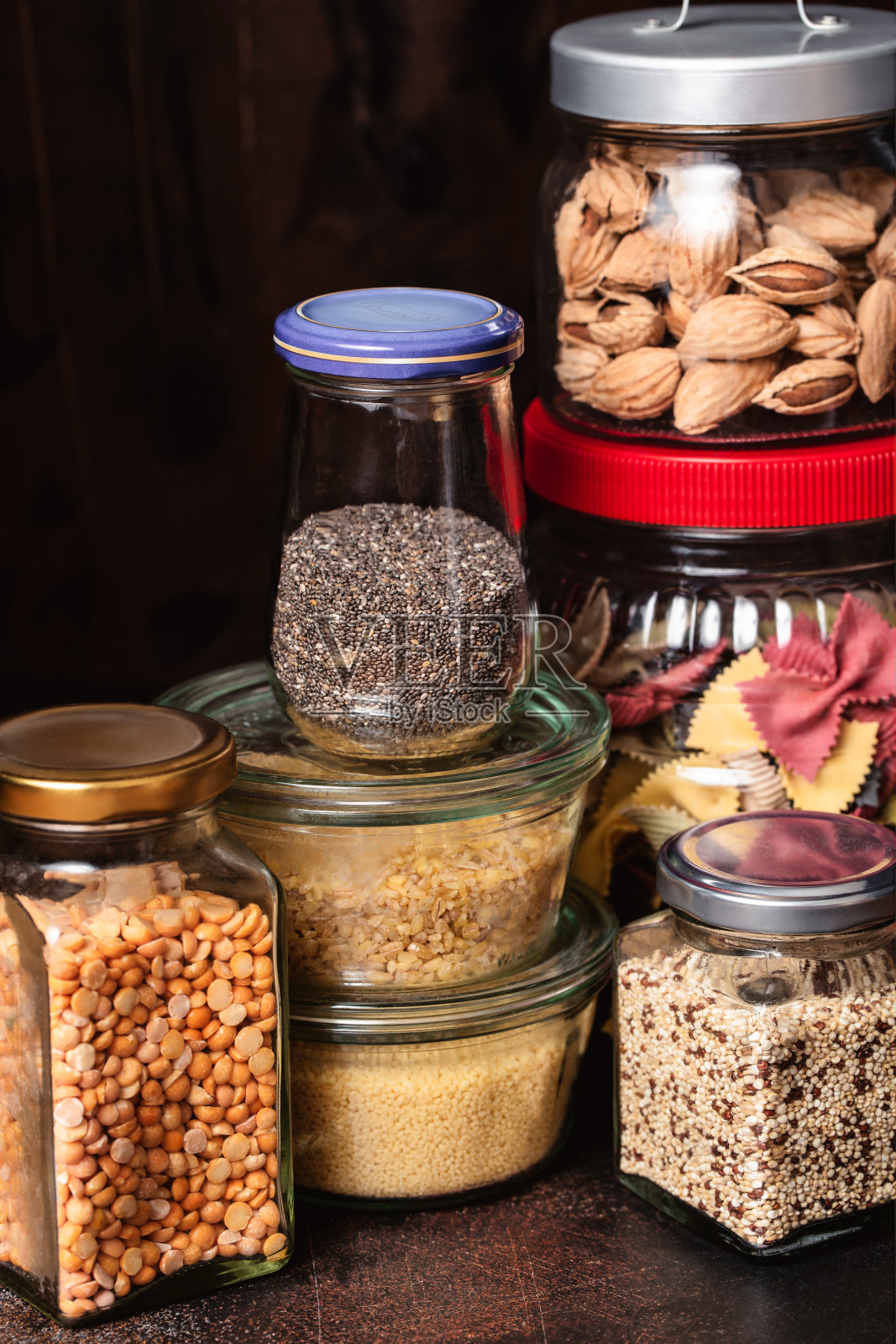 一套谷物，豆类和种子在玻璃罐在黑暗的背景。照片摄影图片