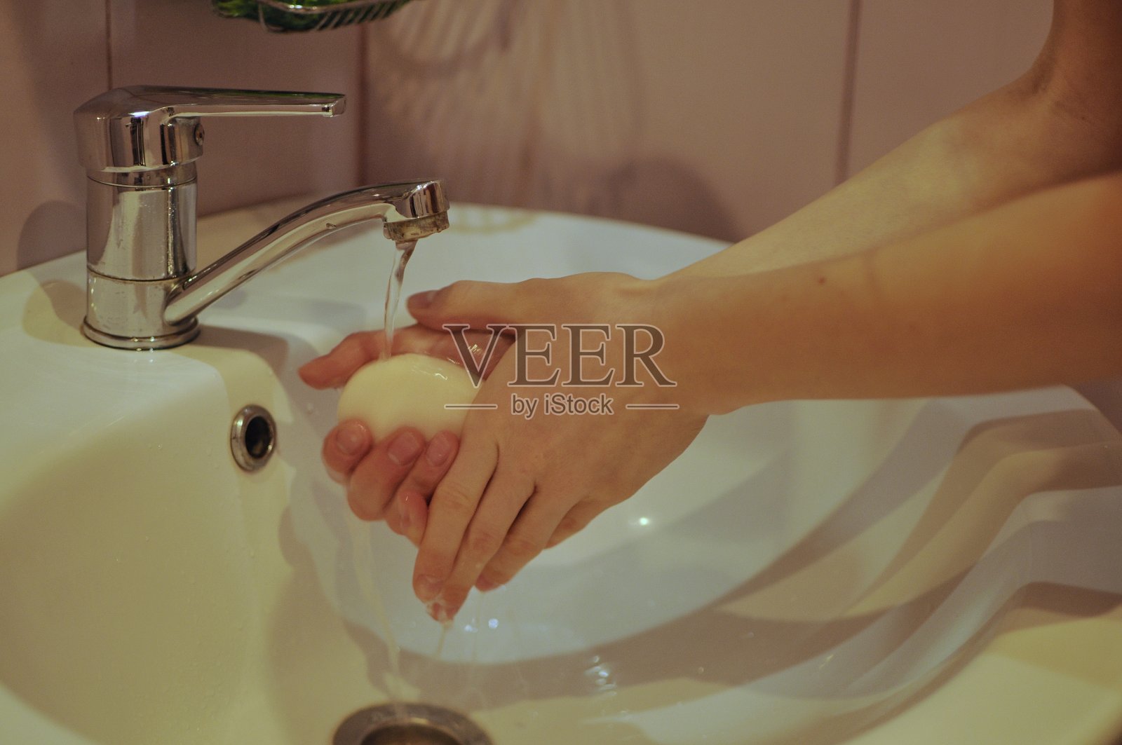 为了预防病毒，妇女在盥洗室里用肥皂仔细洗手照片摄影图片