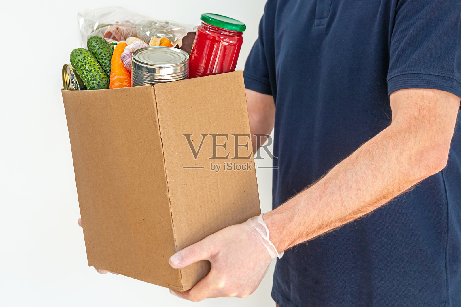 一名志愿者正拿着一个食物捐赠箱，为受新冠肺炎疫情影响的人们提供食物。照片摄影图片