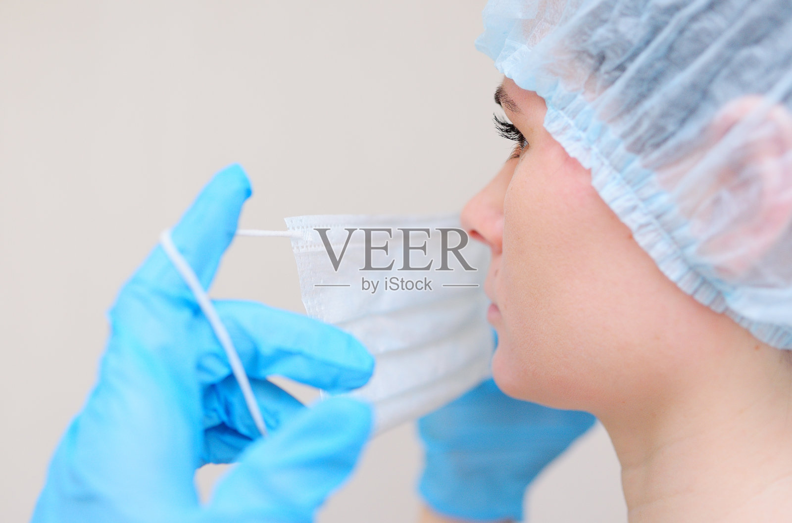 年轻迷人的悲伤的女医生或护士戴上医用口罩，准备在灯光背景下检查病人照片摄影图片