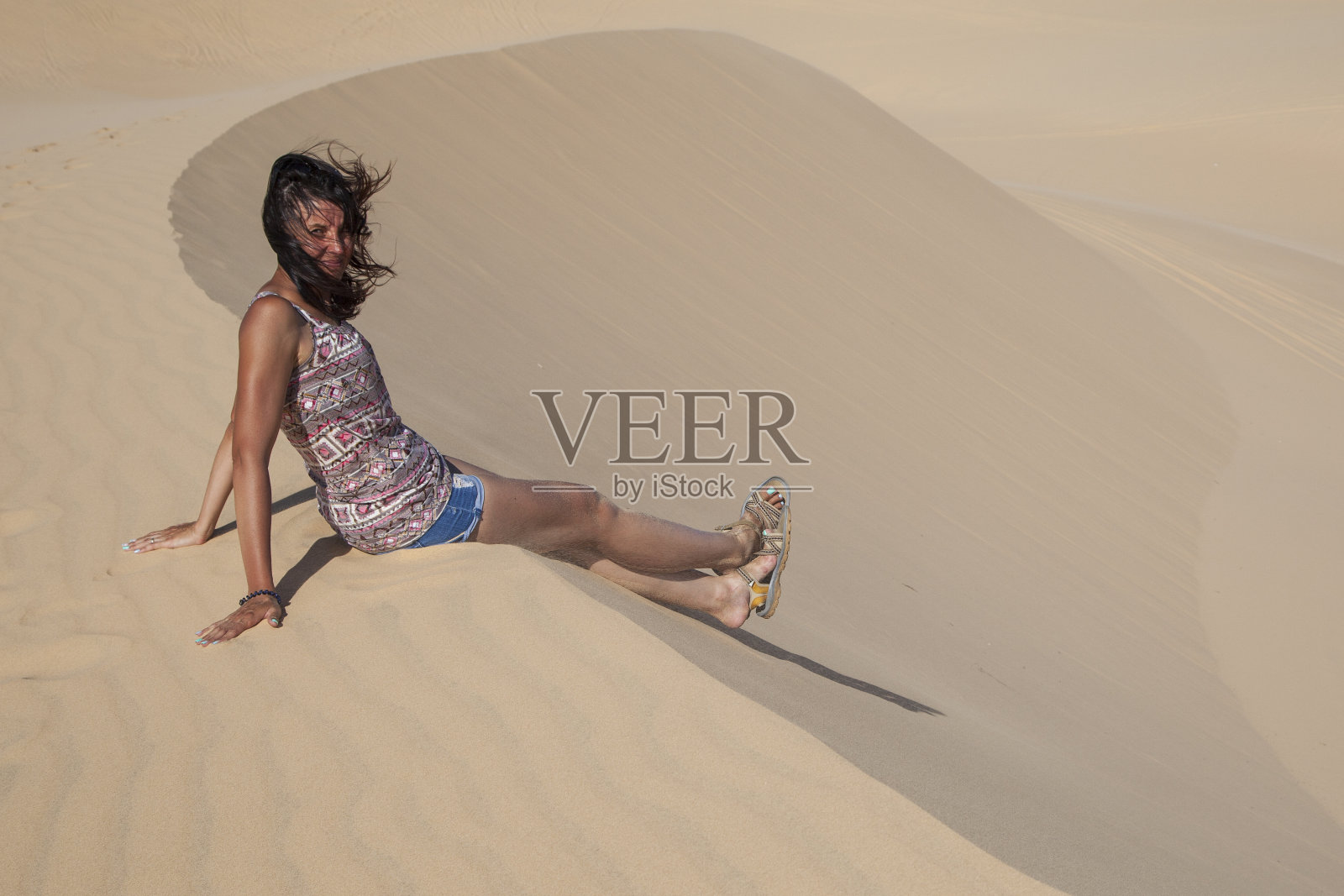 自由的理念，美丽快乐的女孩在沙滩上跳跃，穿着黑色的连衣裙，心情愉悦照片摄影图片