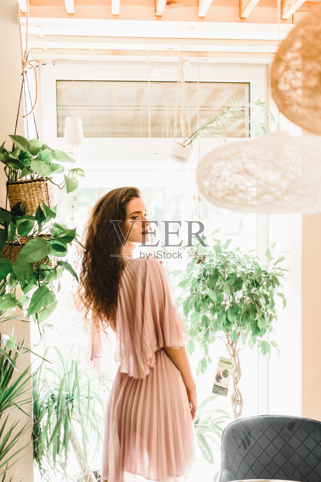 专业模特站在窗户对面，向右侧看。自然美丽的长波浪头发的女人。照片摄影图片