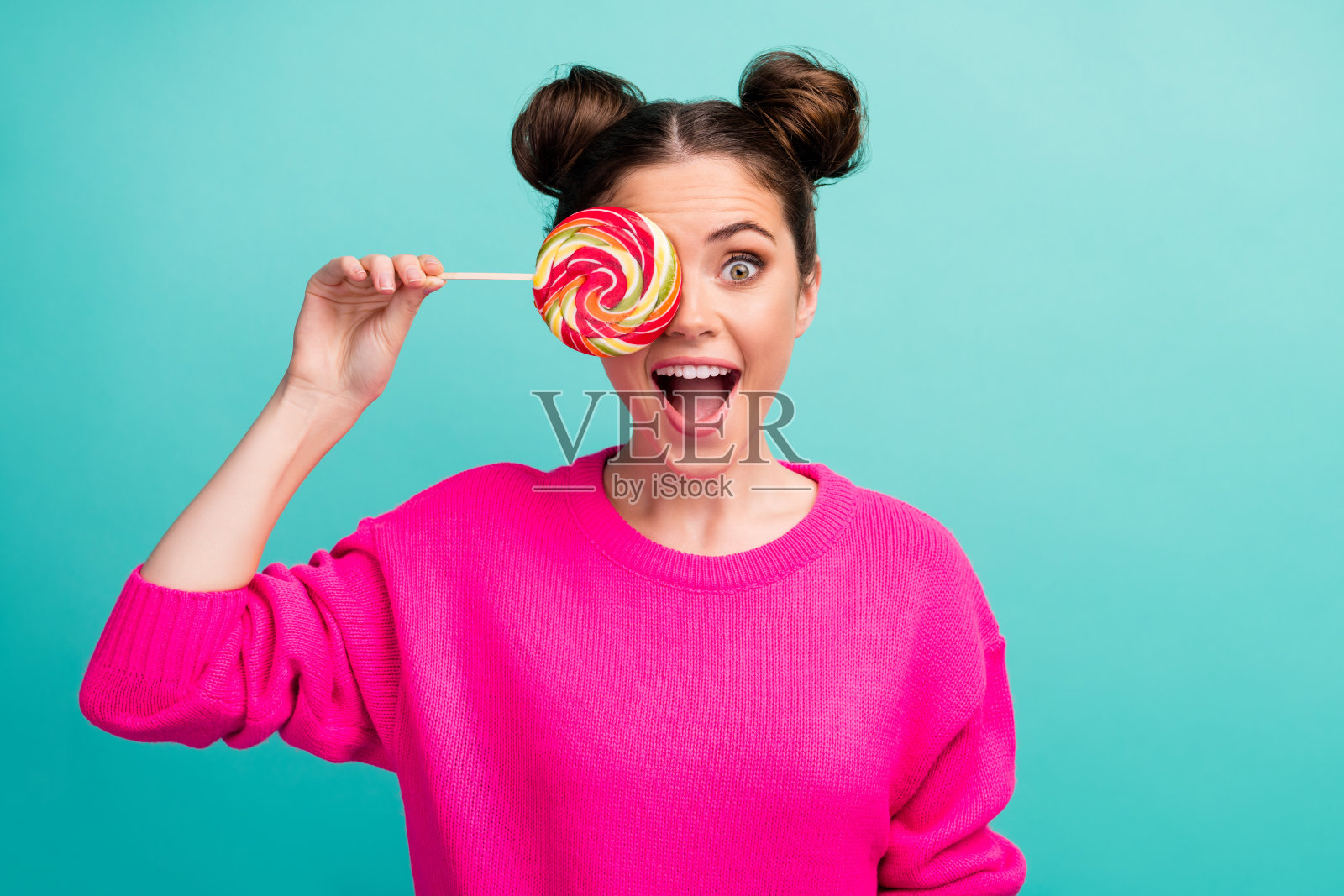 她的特写，她可爱的，迷人的，幼稚的，幽默的，活泼的，愉快的，愉快的卷发女孩闭上眼睛，与棒棒糖隔离在明亮生动的照耀，充满活力的绿色蓝色背景照片摄影图片