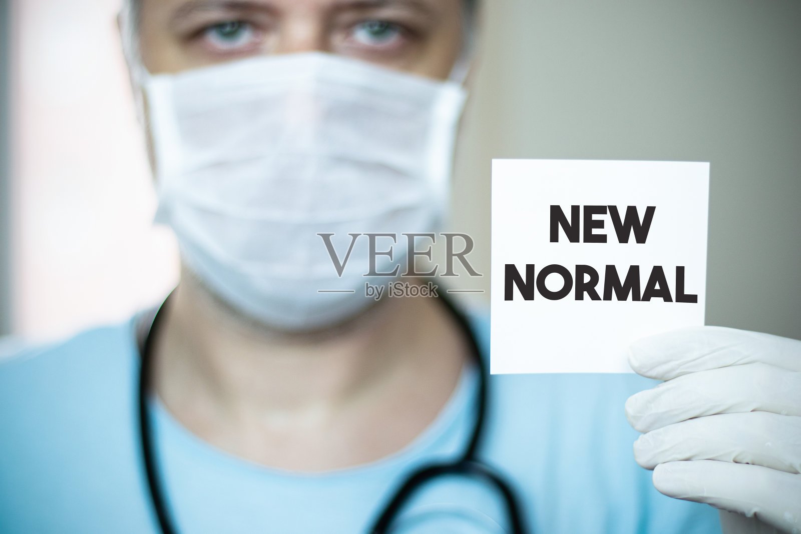 新冠肺炎后的新常态。医生手里拿着一张写着新常态的卡片。照片摄影图片