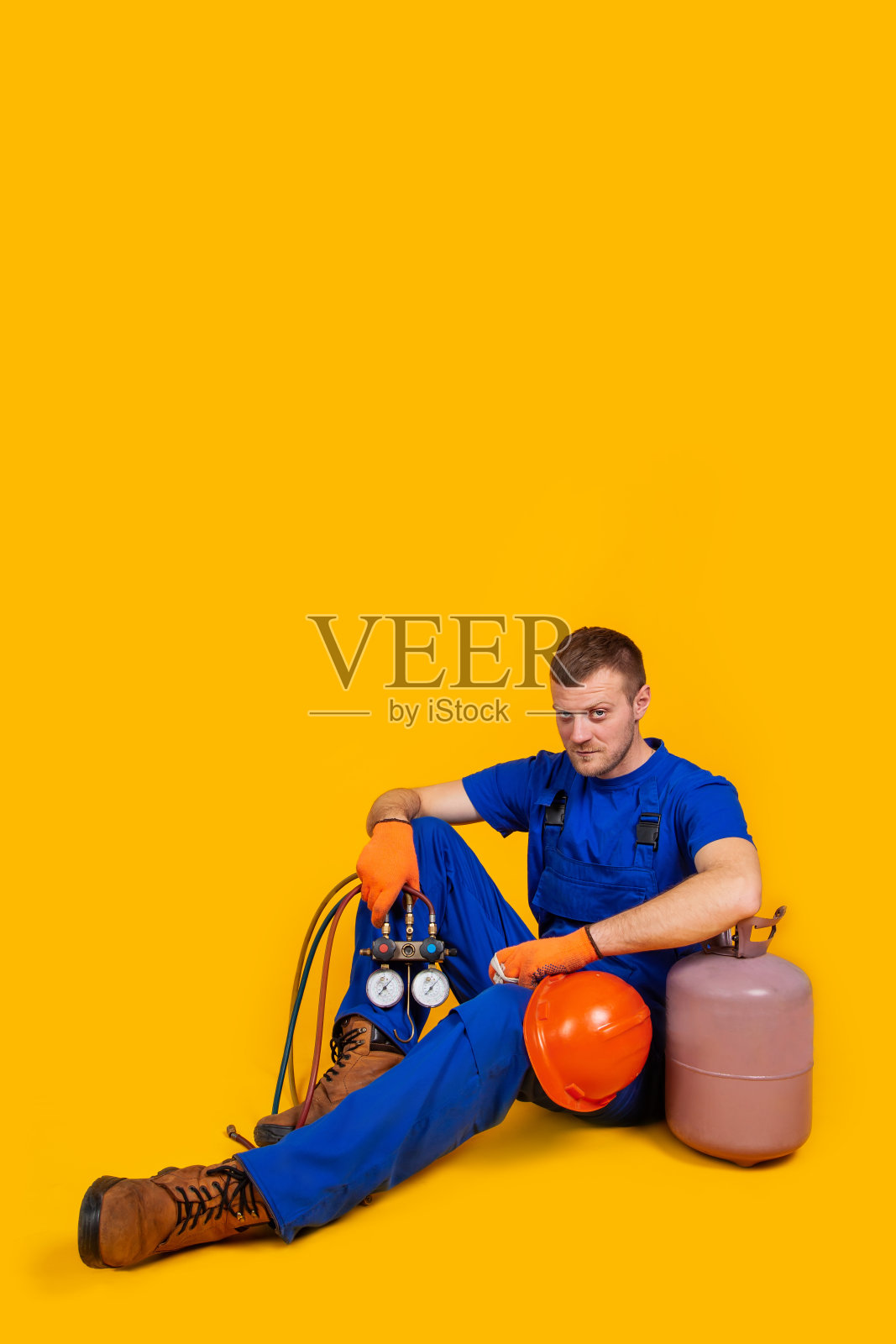 男工穿着工作服坐在地上，因经济衰退而感到失业照片摄影图片