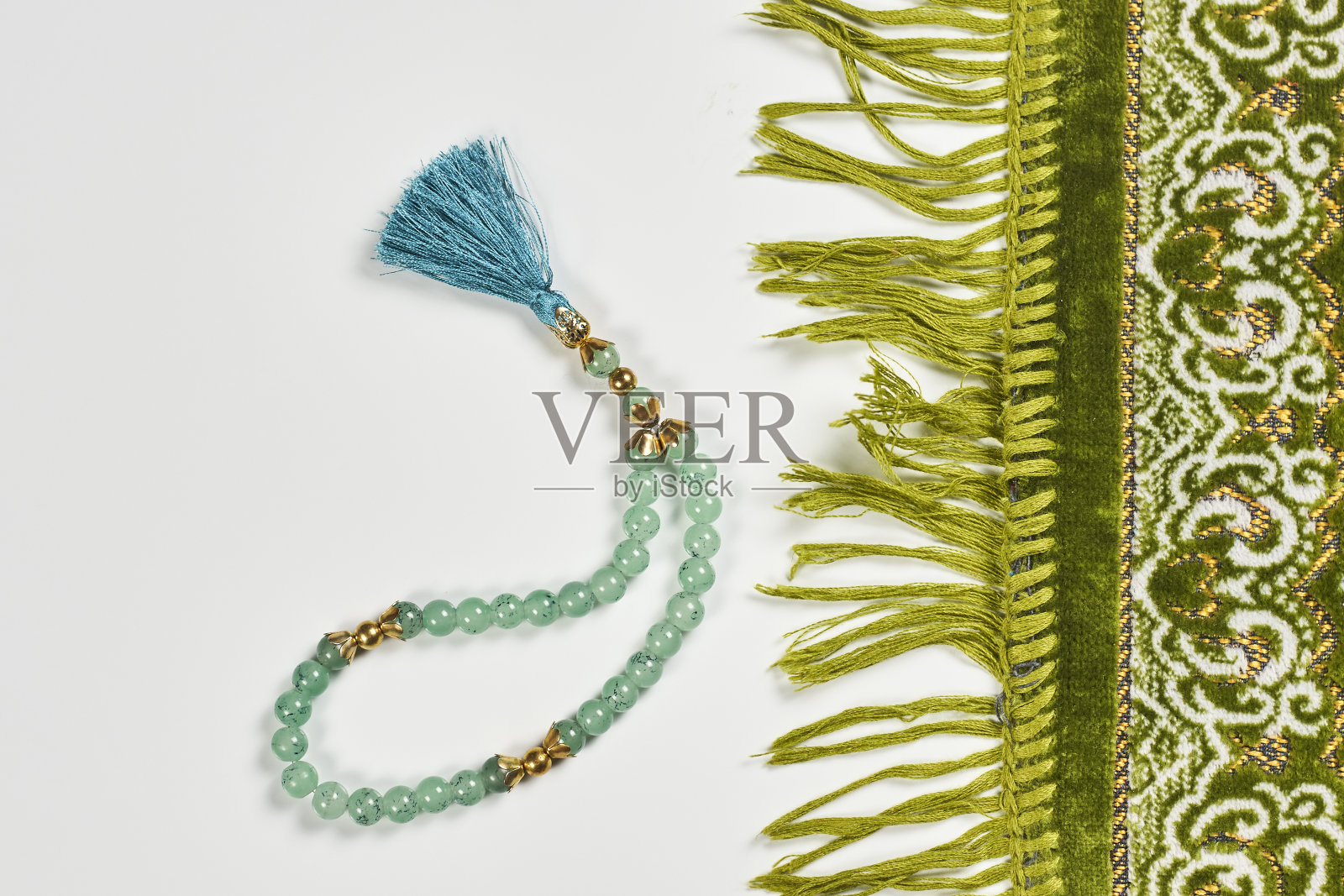 白色背景上的伊斯兰祈祷地毯和念珠照片摄影图片