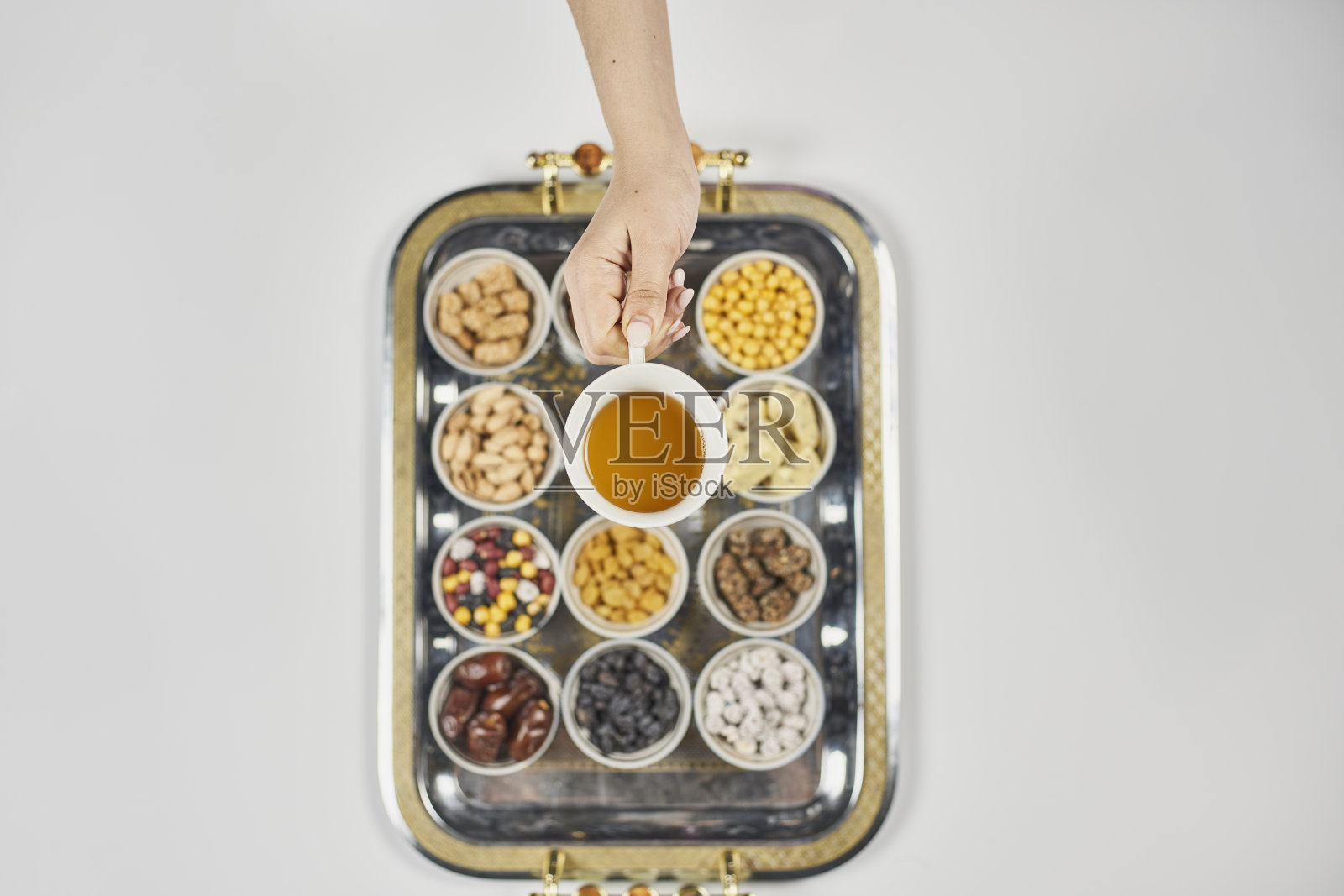 女人手拿一杯茶，背景是传统的阿拉伯开斋节糖果和小吃照片摄影图片