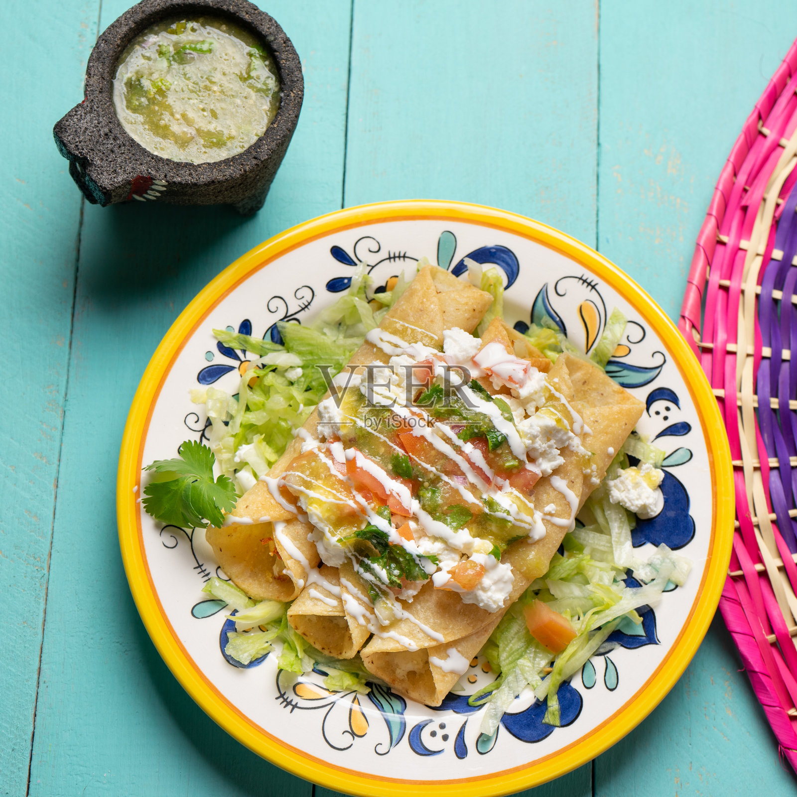 墨西哥土豆和奶酪炸玉米饼也被称为flautas与绿色酱在绿松石背景照片摄影图片