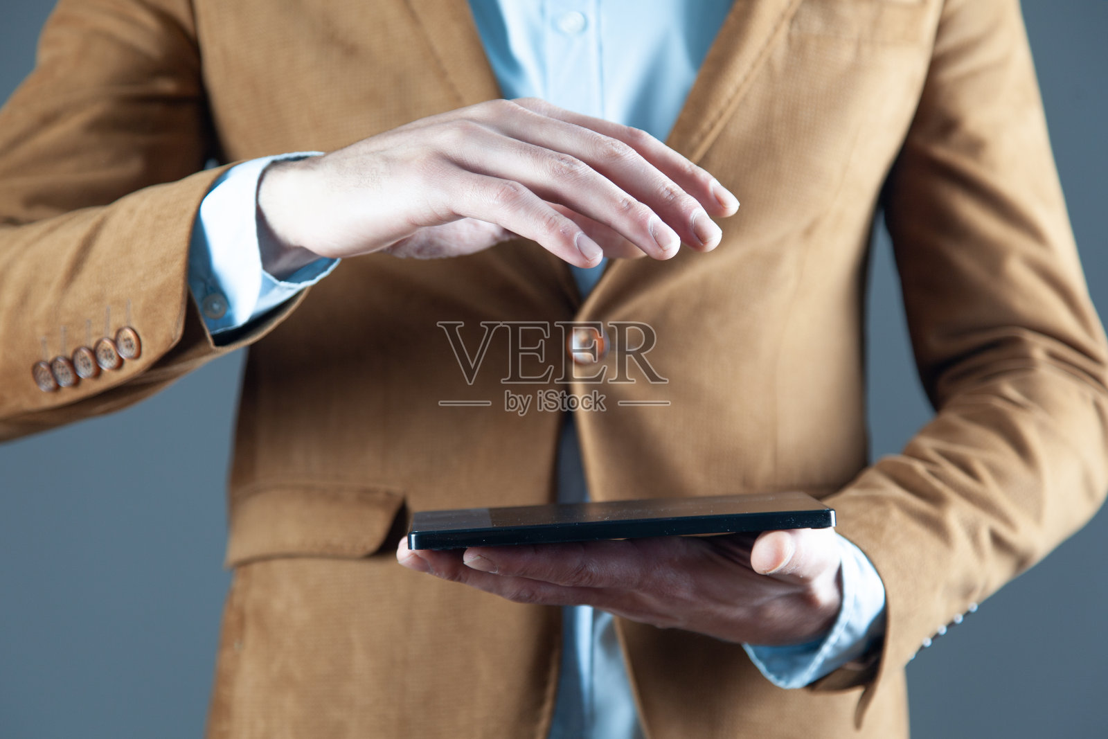 在灰色背景下，男子手持平板电脑照片摄影图片