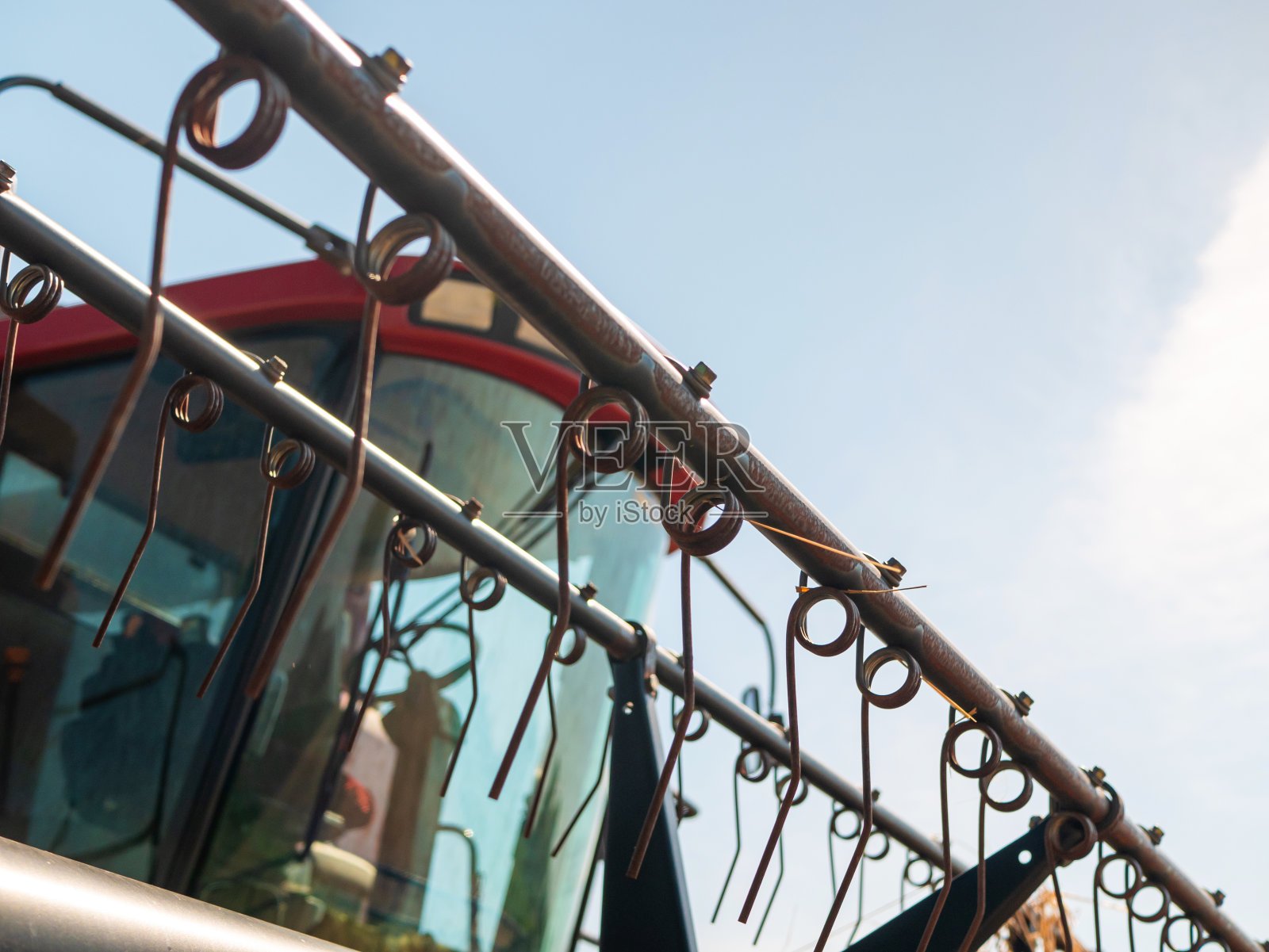 夏天收割小麦。红色收割机在田里工作。黄金成熟小麦收获机是农用田间收割机。照片摄影图片