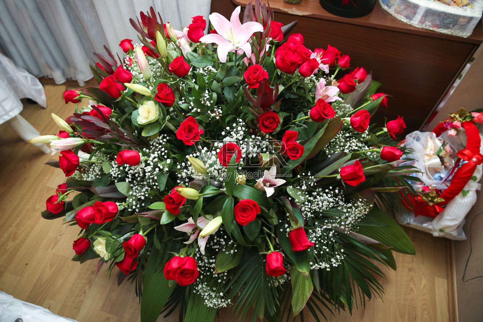 地板上有红玫瑰。生日礼物。一大束美丽的红玫瑰。照片摄影图片