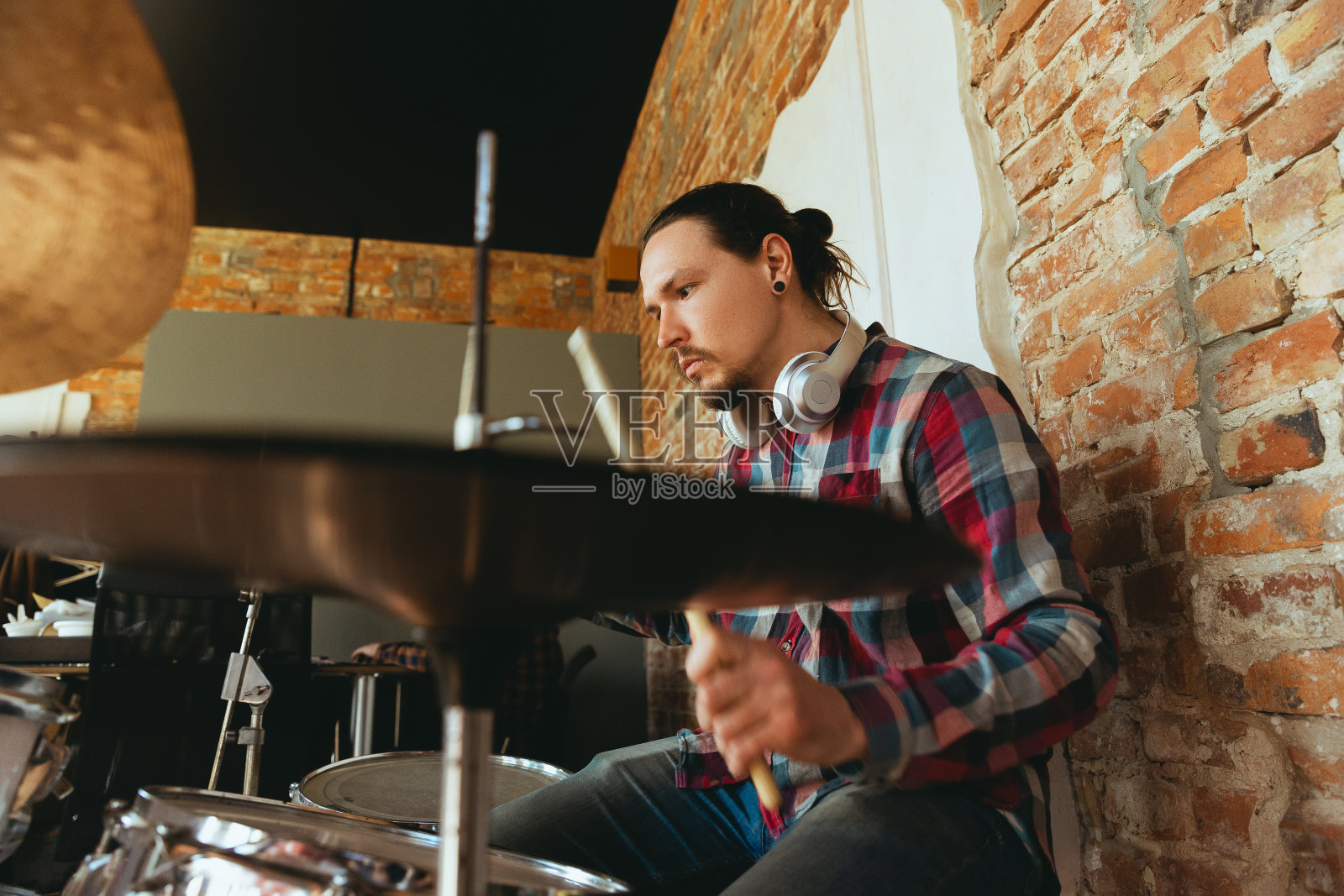 一名白人音乐家在网上与乐队演奏击鼓，在家里被隔离和隔离，灵感即兴创作，近距离照片摄影图片