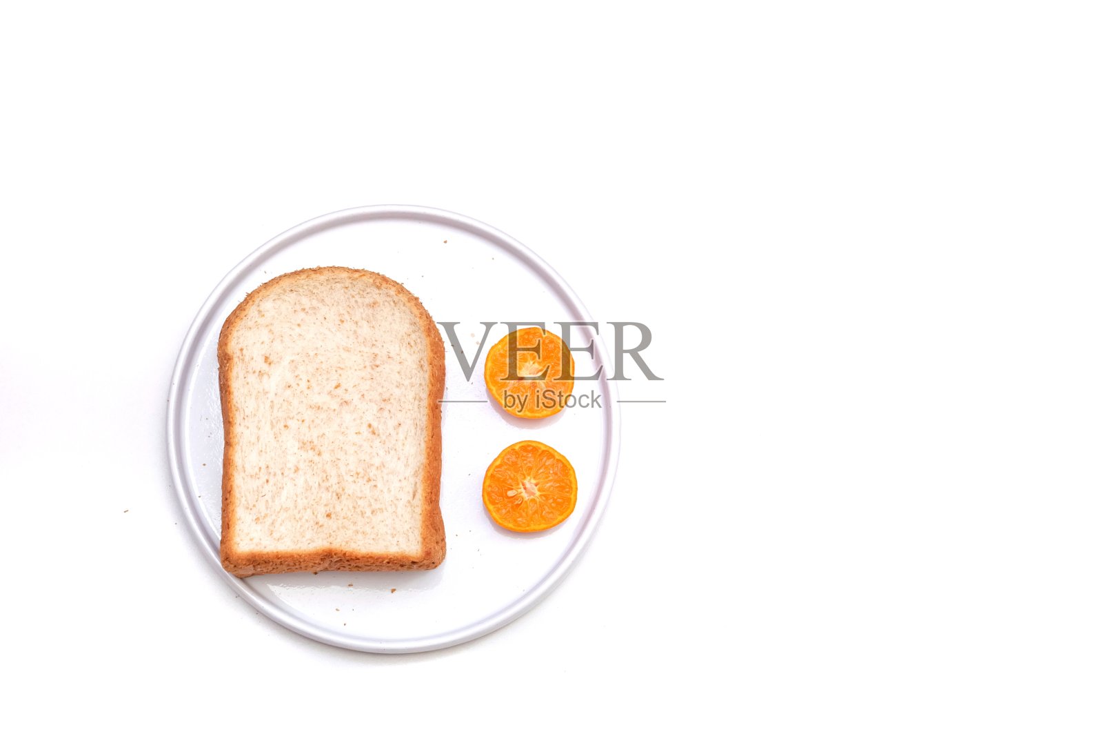 一片切成薄片的全麦面包和切了一半的橙子放在一个白色的盘子里照片摄影图片