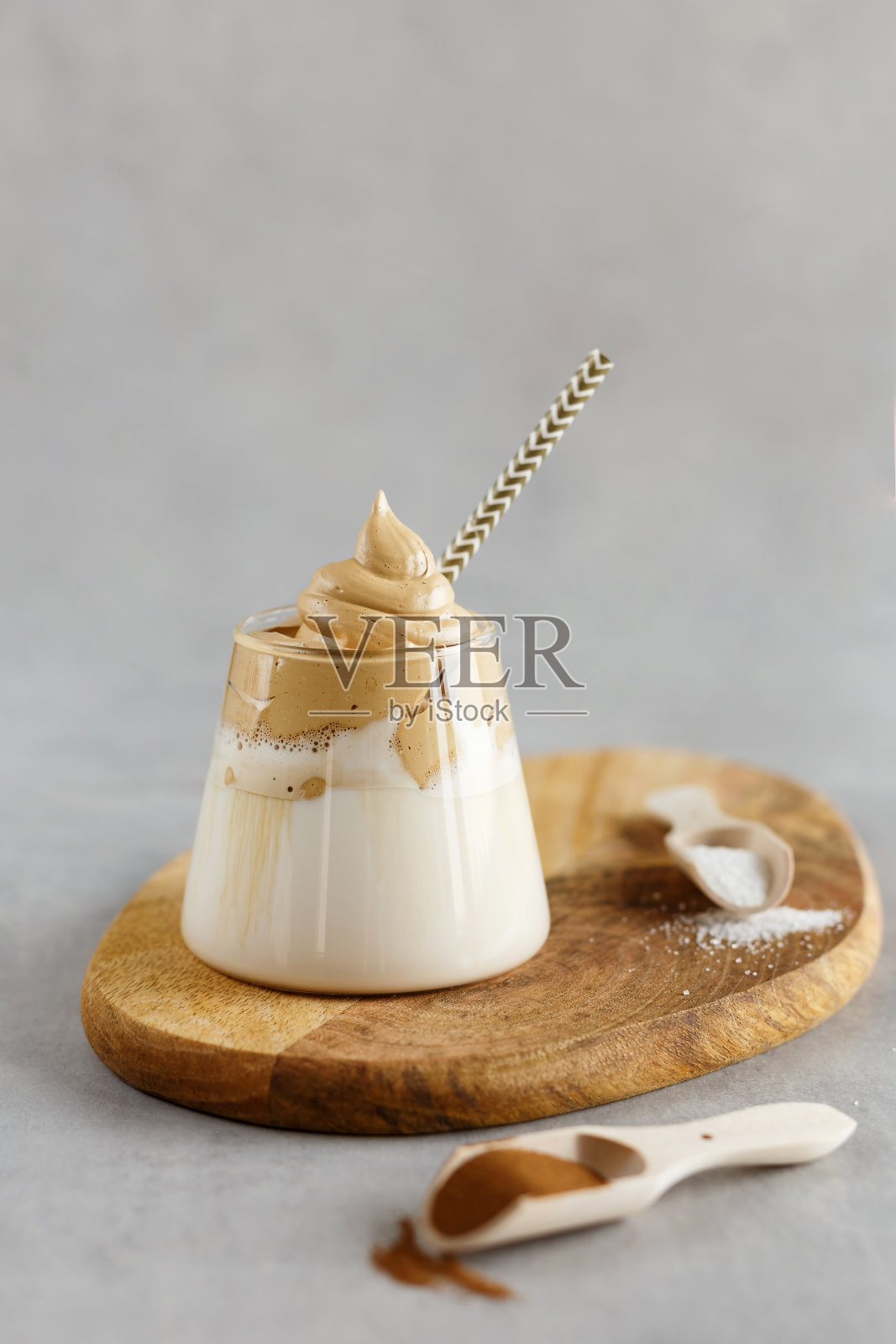 韩国饮料。自制达尔戈纳咖啡在玻璃与牛奶在灰色的背景。时髦的蓬松奶油泡过的咖啡。木站。照片摄影图片