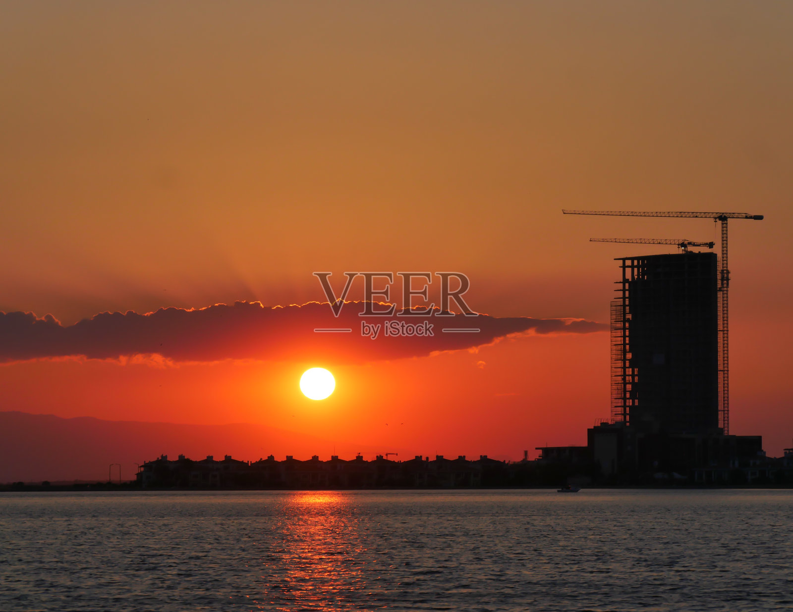 建筑与摩天大楼和起重机映衬着阳光下五彩缤纷的天空。照片摄影图片