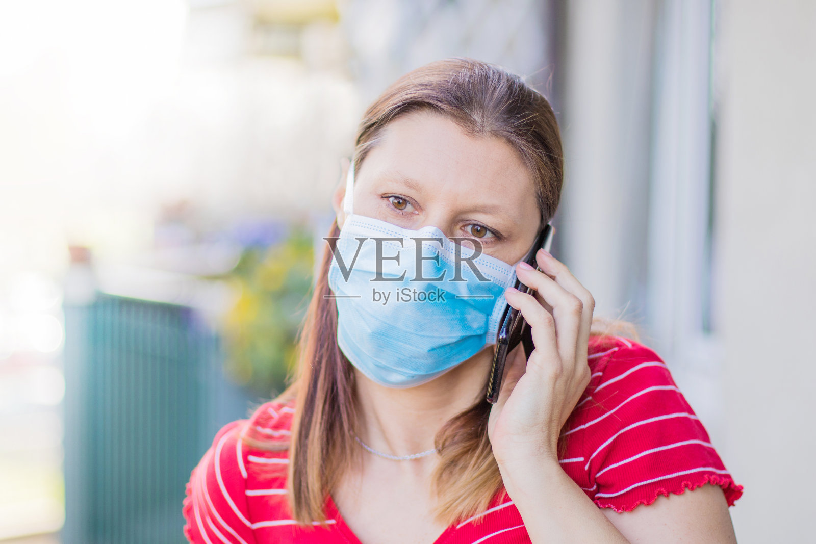 由于新冠肺炎大流行，戴口罩的妇女在隔离期间外出使用手机。照片摄影图片