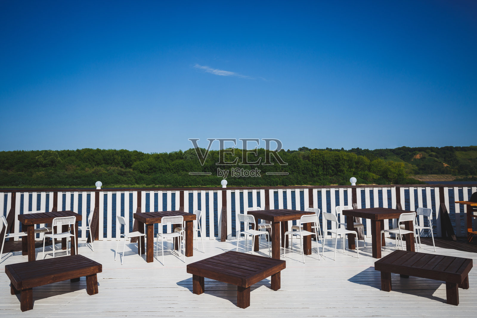 楼梯平台上有咖啡桌和椅子。看到河对岸的绿色森林。晴朗的天气。照片摄影图片