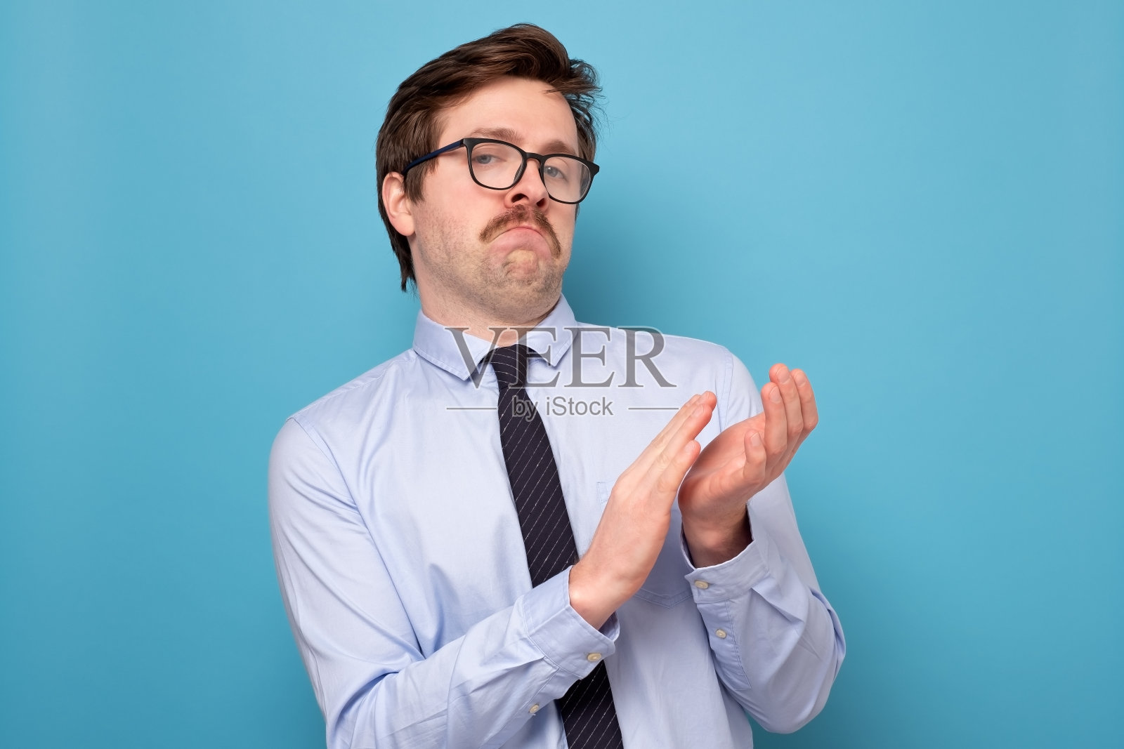 戴着眼镜，穿着蓝色衬衫的快乐商人站着鼓掌照片摄影图片