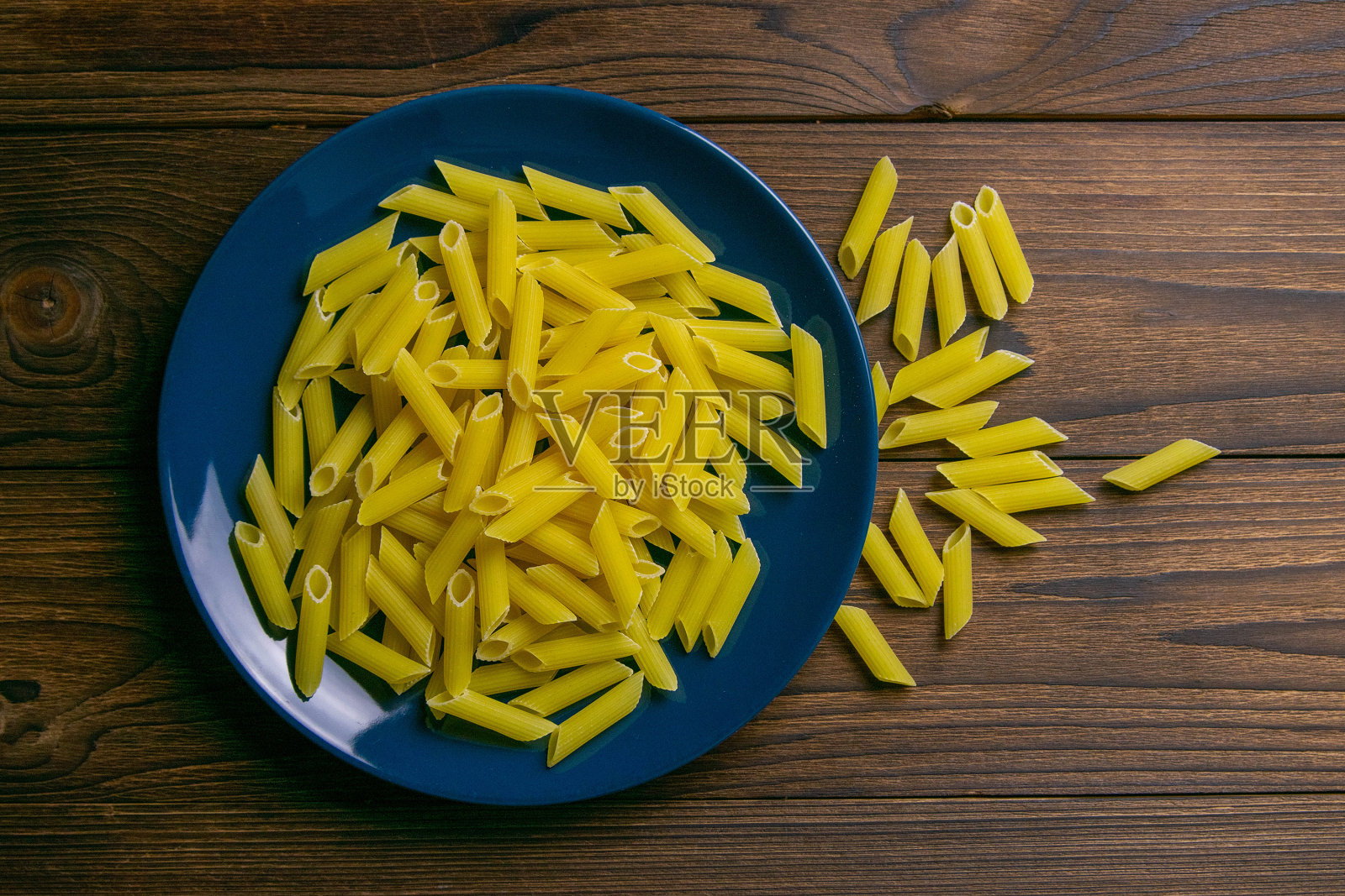 在黑色木背景上的蓝色盘子里的青色意大利面。上面的观点照片摄影图片