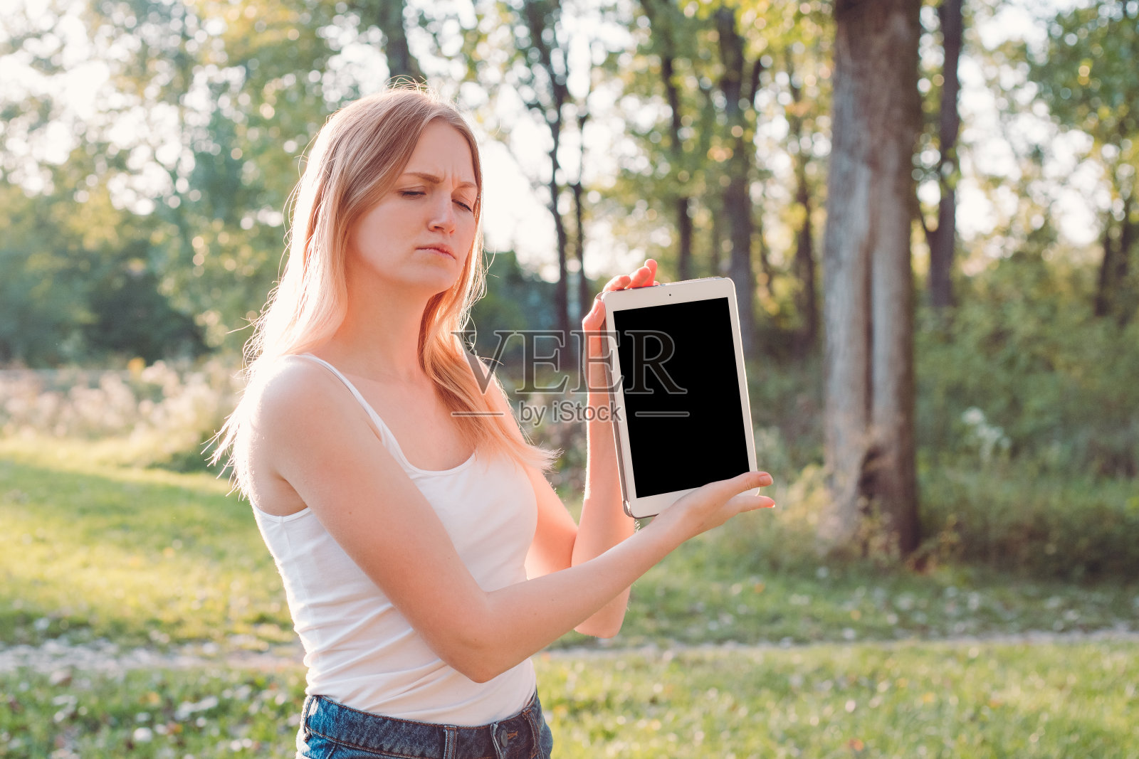 年轻的白人妇女的肖像担心感到压力。强烈的情感，滑稽的面部表情。女孩使用平板电脑与孤立的白屏作为模型。照片摄影图片