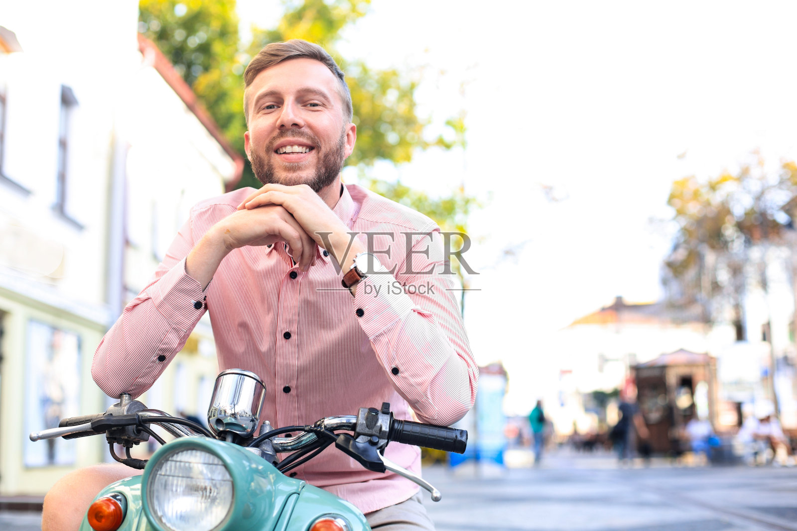 英俊的男人在一个假期的背景下摆摩托车的姿势。街头时尚和风格。照片摄影图片