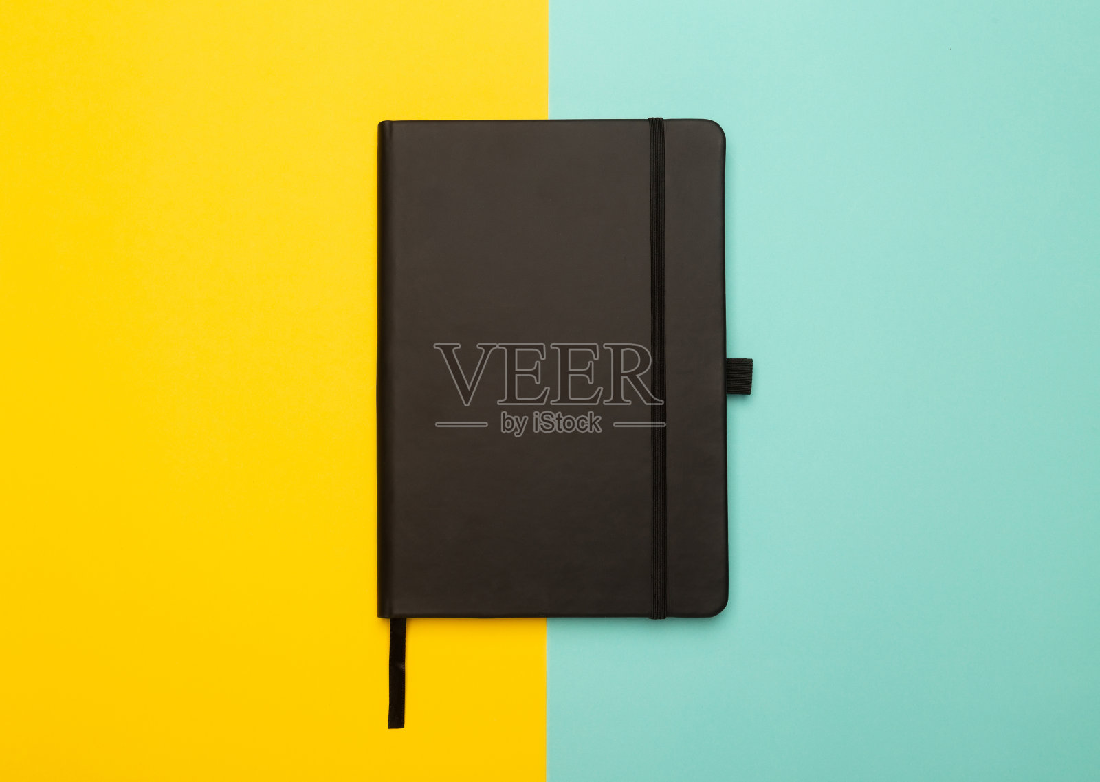 黑色笔记本孤立在黄色和蓝色的背景。平铺或顶视图角度照片摄影图片