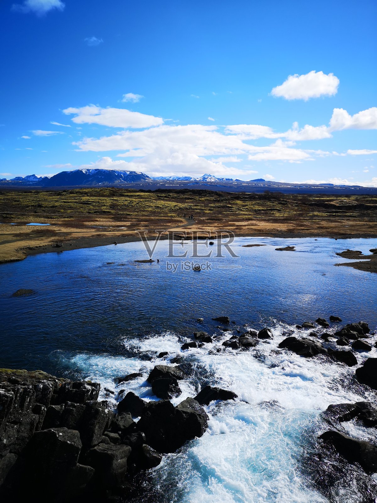 在平维利尔国家公园美丽的山前，小瀑布流入湖中。照片摄影图片