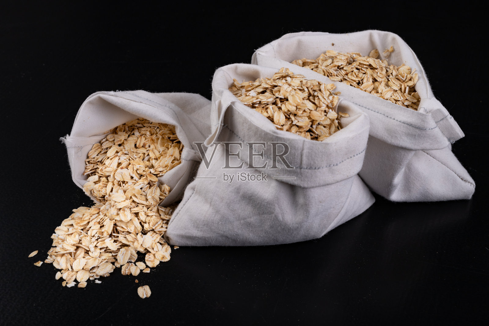 白布袋里的燕麦片。健康的食物最好是早餐。黑暗的背景。照片摄影图片