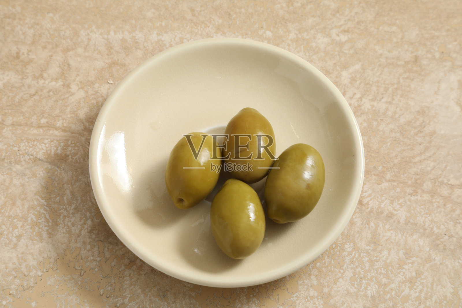 桌上的杯子里有四颗绿橄榄照片摄影图片