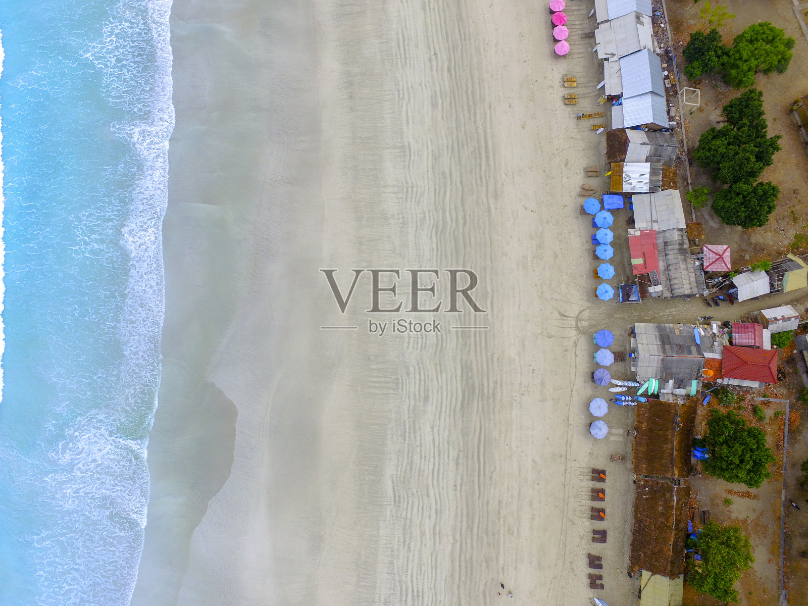 在龙目岛海滩上，可以看到空荡荡的沙滩，配有遮阳伞和沙滩椅，绿松石般的海水照片摄影图片