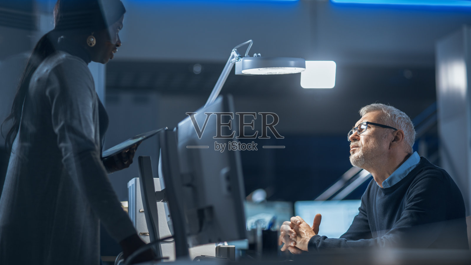 男工业工程师与女经理谈论新型高效发动机概念设计的镜头。由工业工程师和科学家组成的多元化国际团队在开发中心工作。照片摄影图片