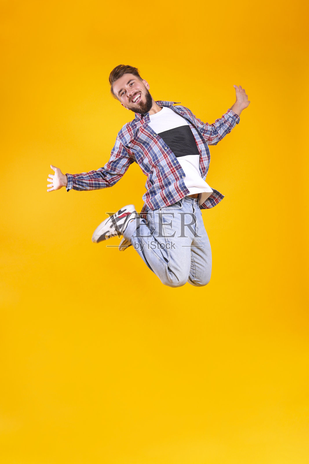 年轻英俊的男子与面部毛发跳过黄色墙与大量的文本复制空间。肖像自信的胡须男性，穿着时尚的休闲服装。孤立的,背景。照片摄影图片