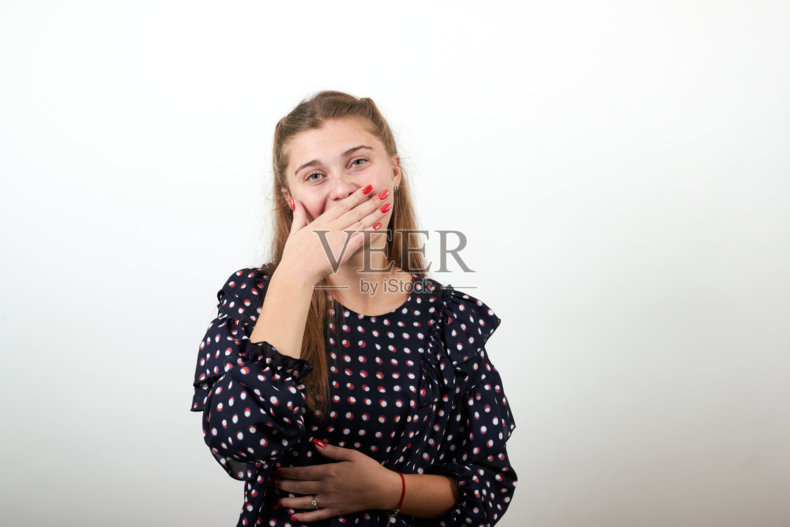 女孩穿着黑色的裙子，用白色的圆圈遮住她的嘴，用手微笑照片摄影图片