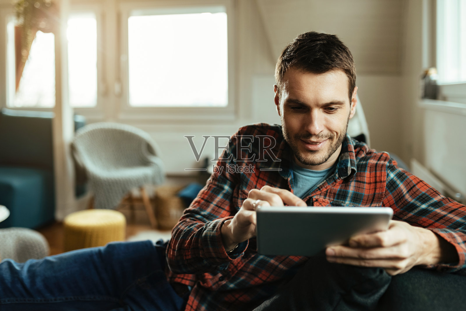 微笑的男人在客厅的触控板上上网。照片摄影图片