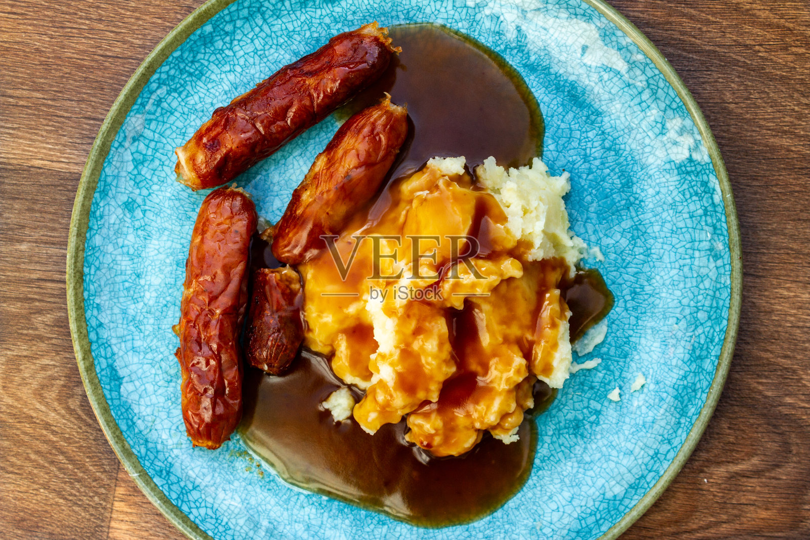 传统的土豆泥，香肠和肉汁放在绿松石盘子里照片摄影图片