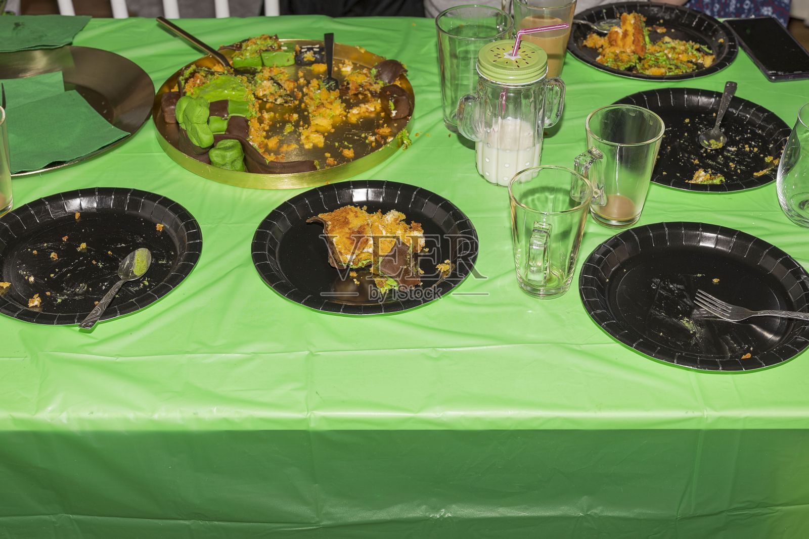 近距离观看桌子与黑色盘子上的蛋糕后生日派对。背景是绿色桌布。照片摄影图片