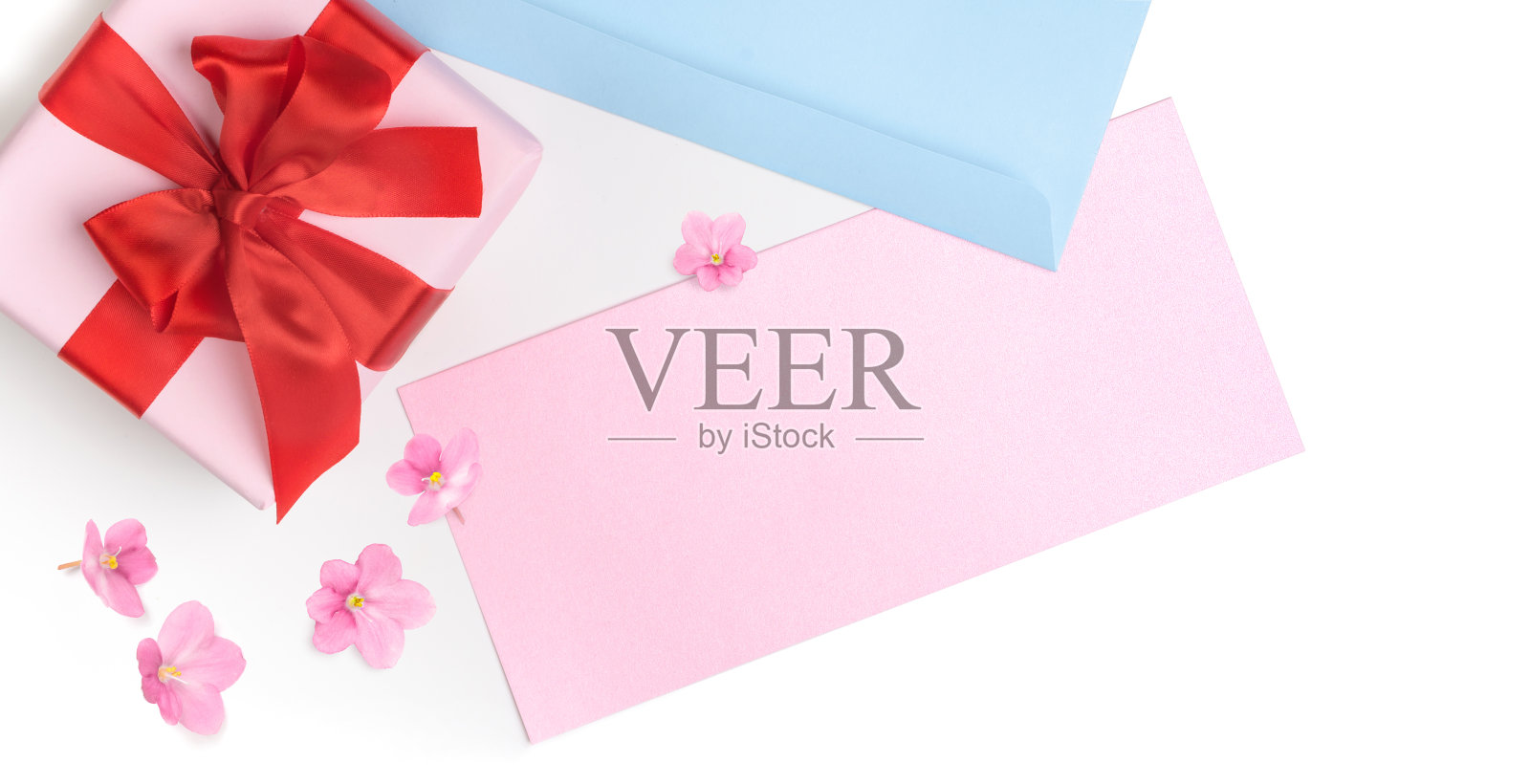 粉红色的礼盒与红色的蝴蝶结和空白的贺卡，情人节，情书或婚礼邀请。前视图。白色的背景上点缀着粉红色的花朵。照片摄影图片
